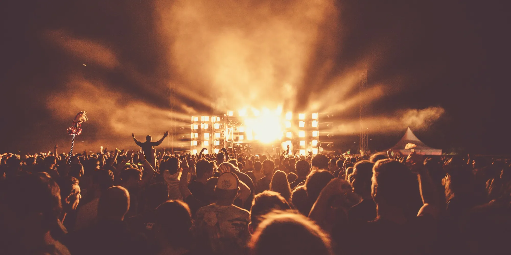 A crowd in front of a brightly lit festival stage